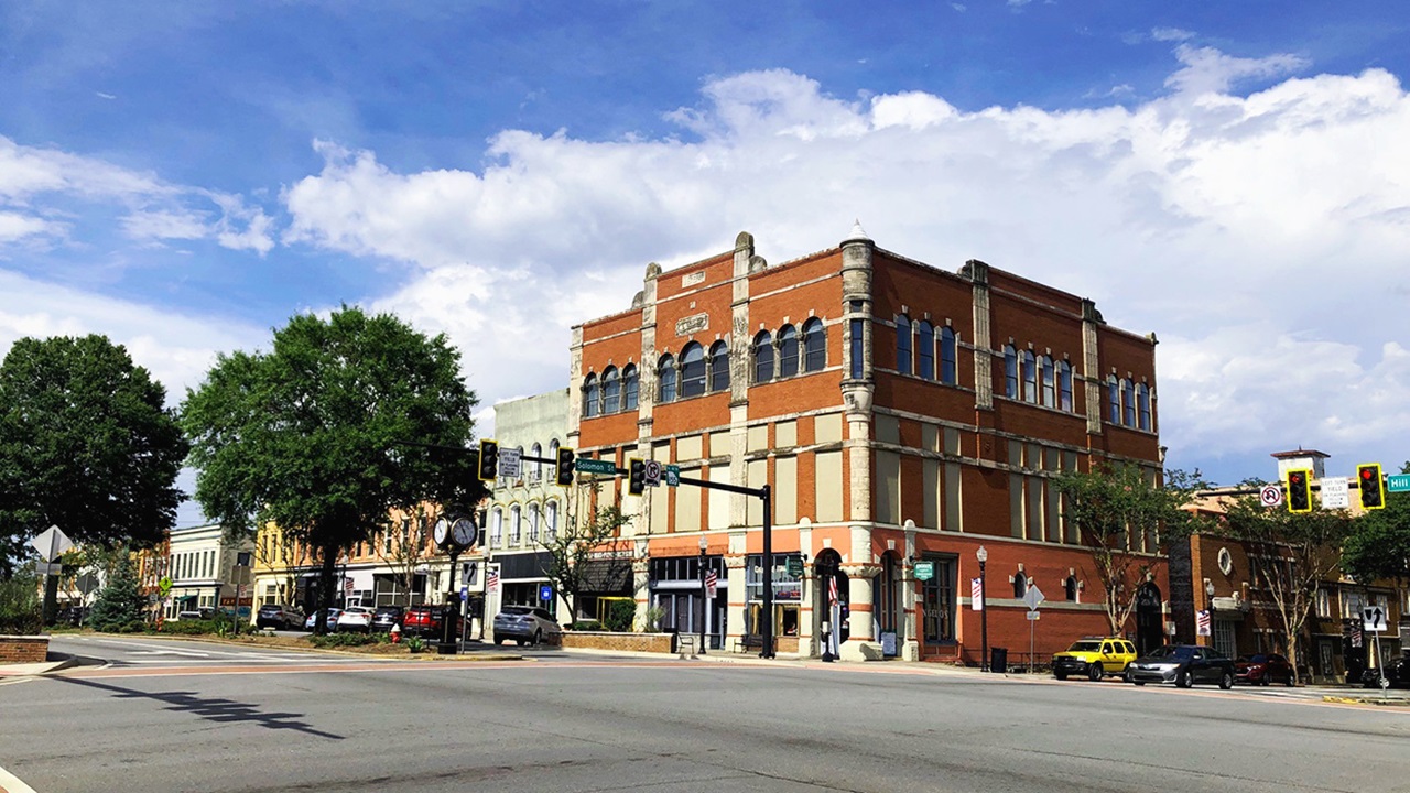 Downtown Griffin, Georgia — the historic brick commercial blocks at the corner of Hill Street and Solomon Street under a blue sky